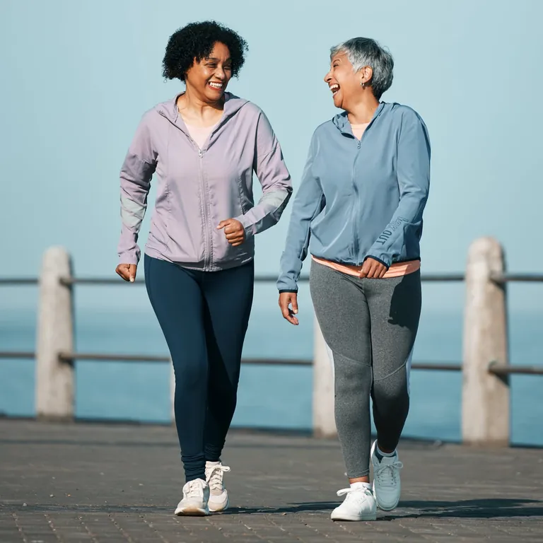 Two women walking along a seaside promenade